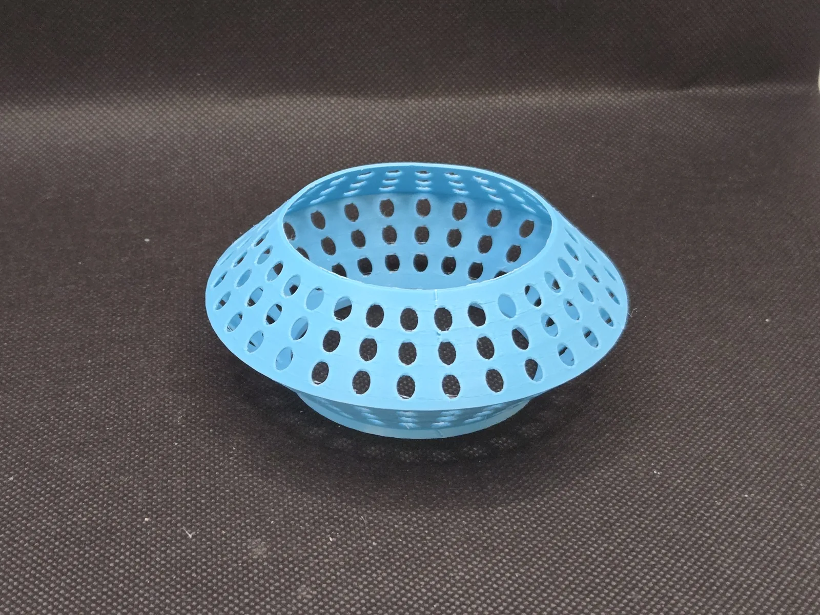 The same perforated blue ring seen from a lower angle, showing the opening through its centre.
