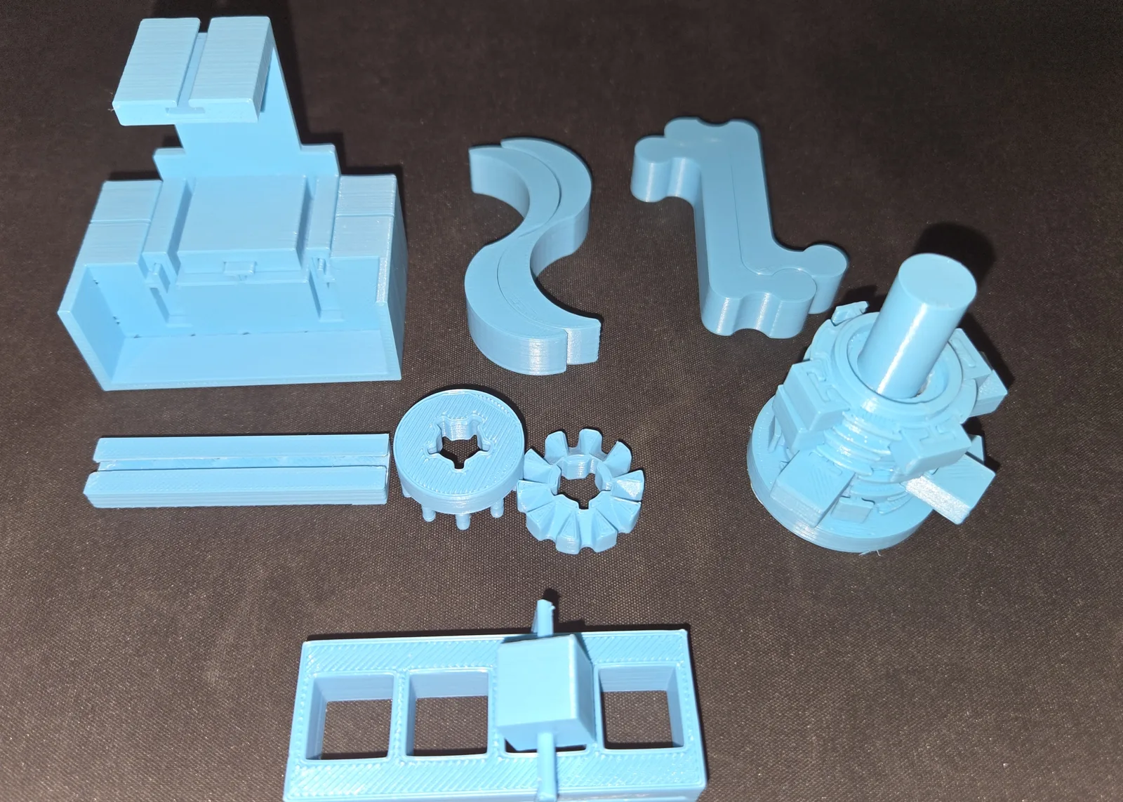 Printed light blue parts of a twisting toy laid out together on a dark surface.